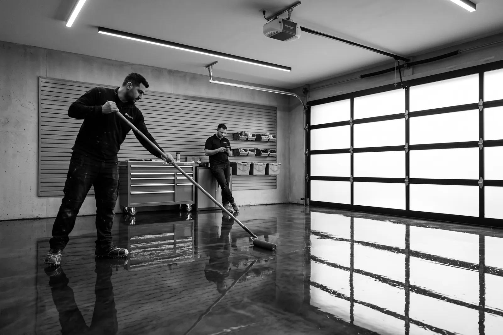 Crew spreading a glossy epoxy floor in a modern garage