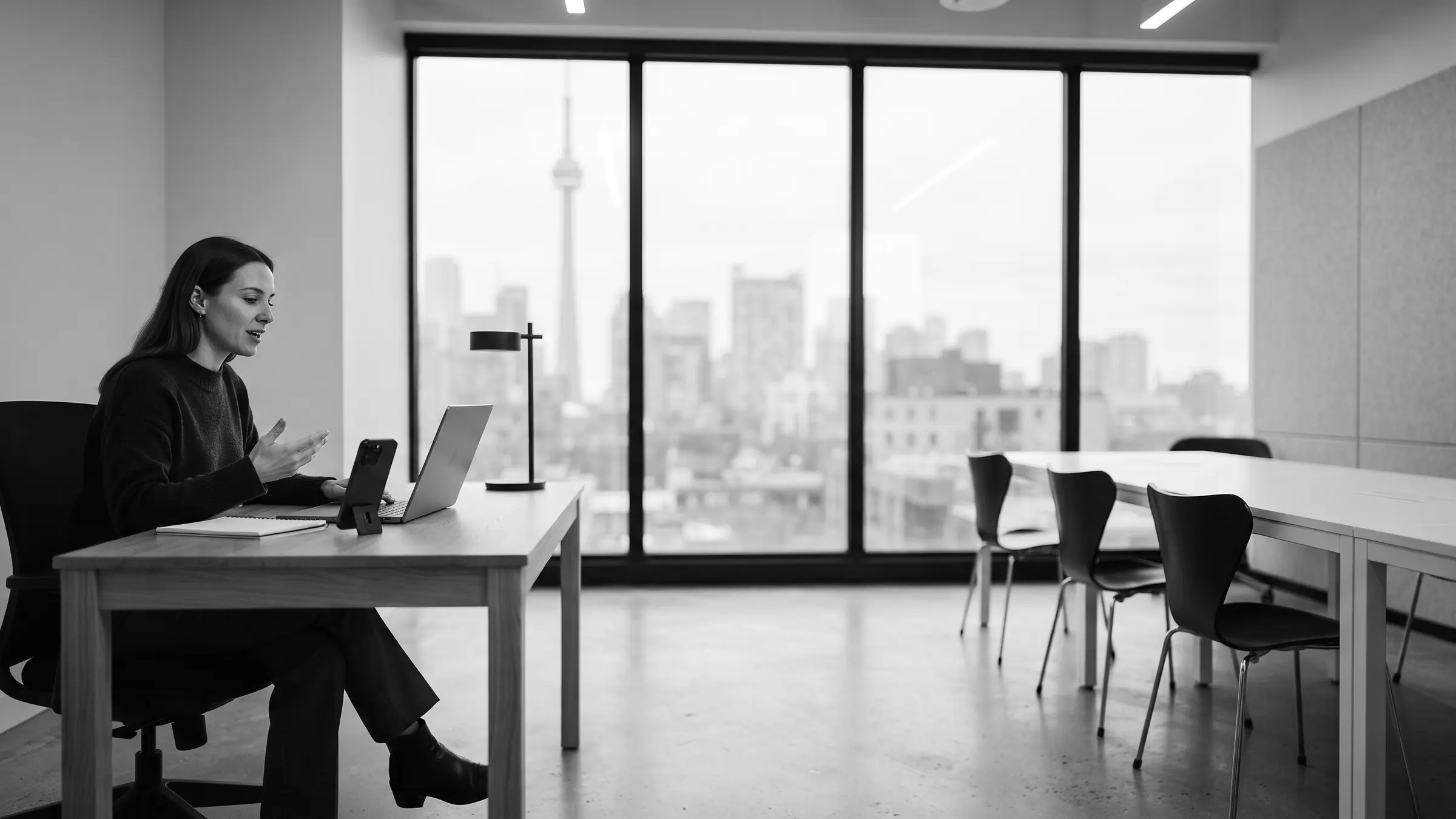 A person at a laptop in a bright minimalist office overlooking the city