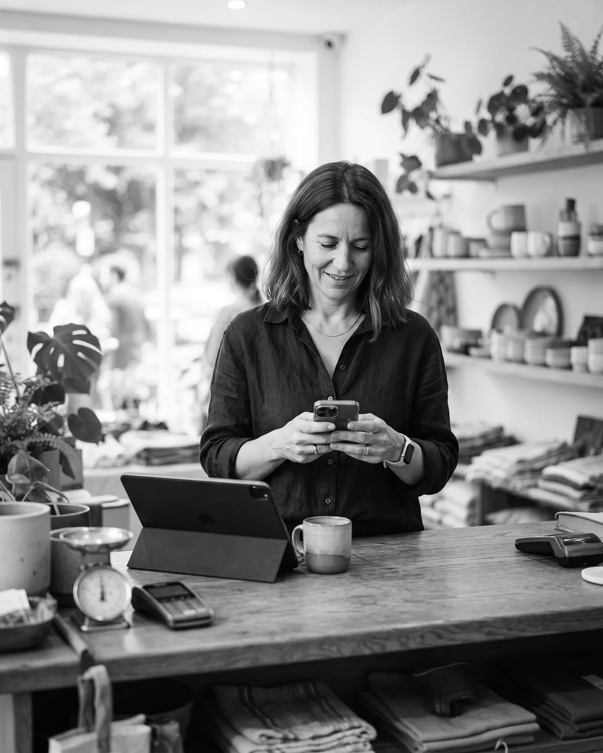 A shop owner updating her Google profile from her phone at the counter