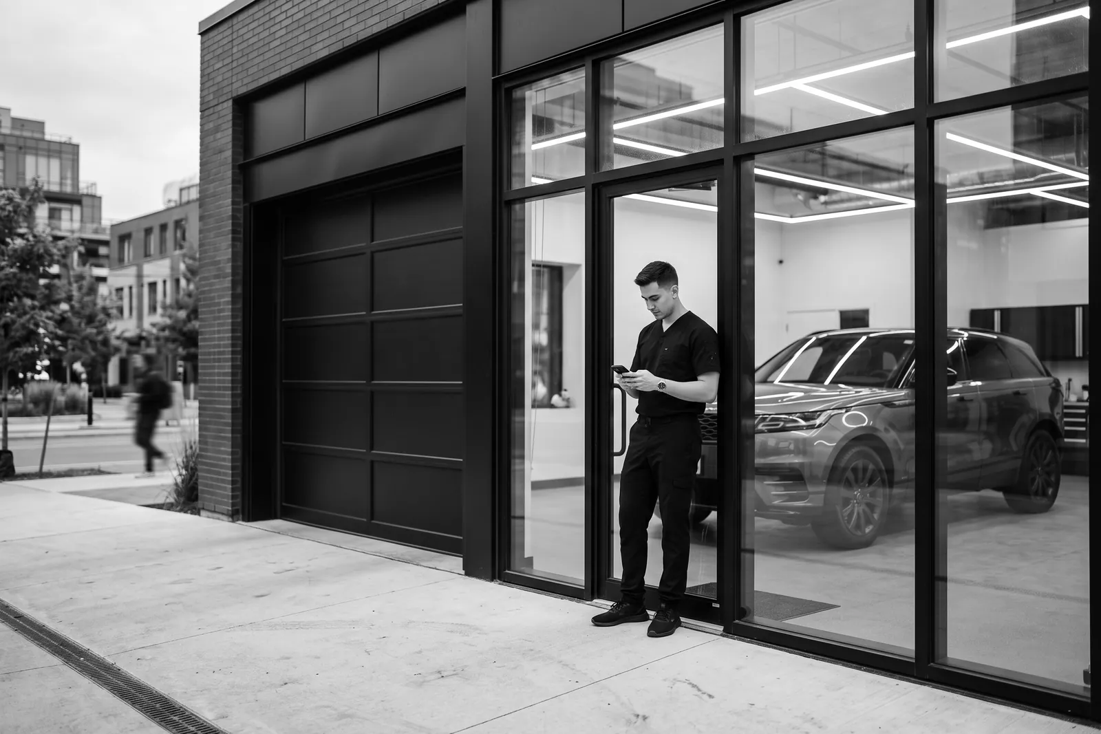 Business owner checking a phone outside a modern glass storefront