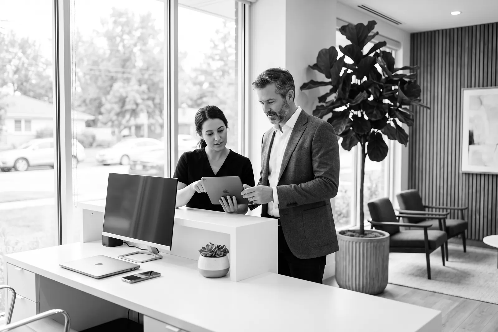 Owner and office manager reviewing a tablet at a modern front desk